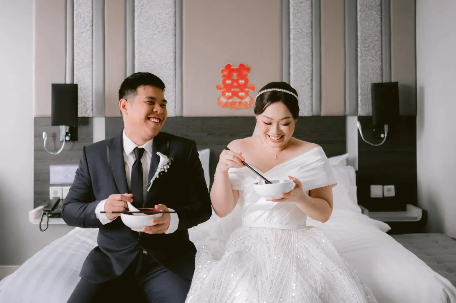 Pengantin makan onde bersama, dengan aksara kebahagiaan ganda di dinding