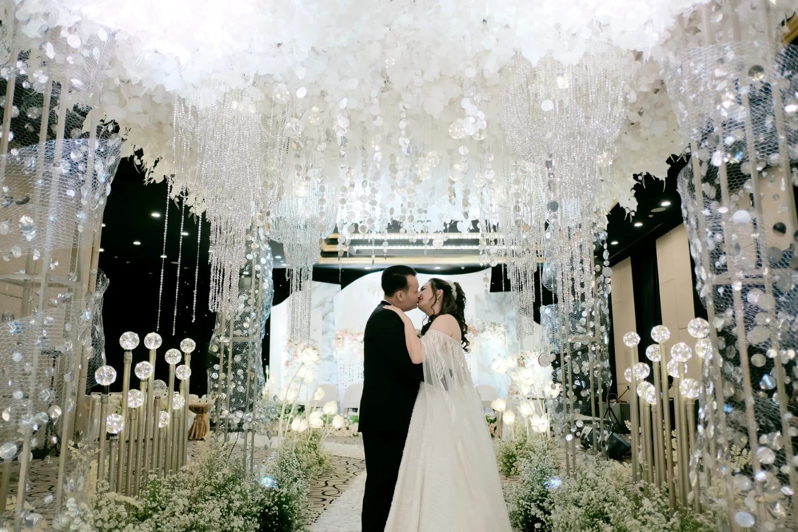 Lorong ballroom berhias kristal dengan pengantin di ujungnya