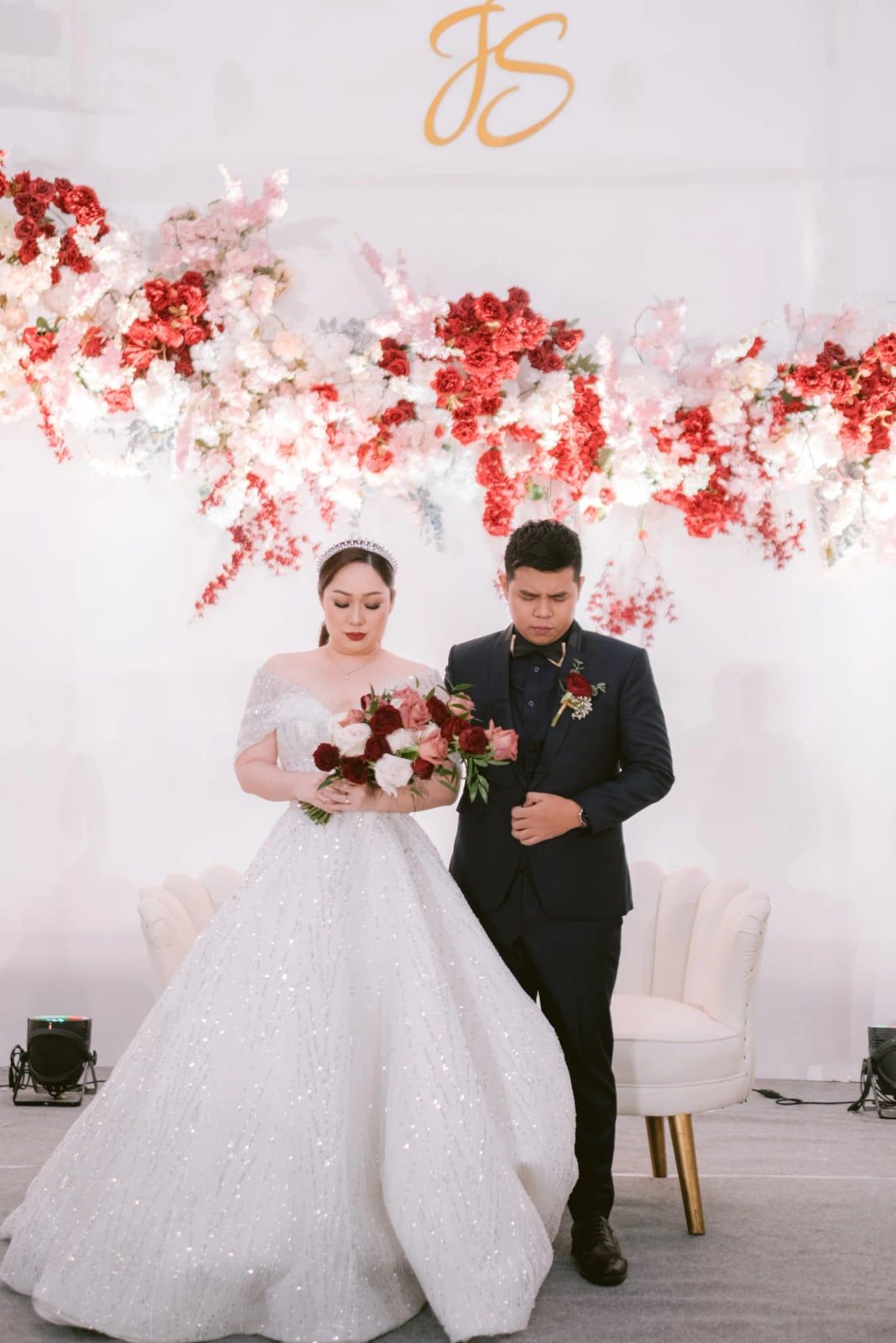 Pengantin berjalan di depan dekorasi bunga merah dan putih