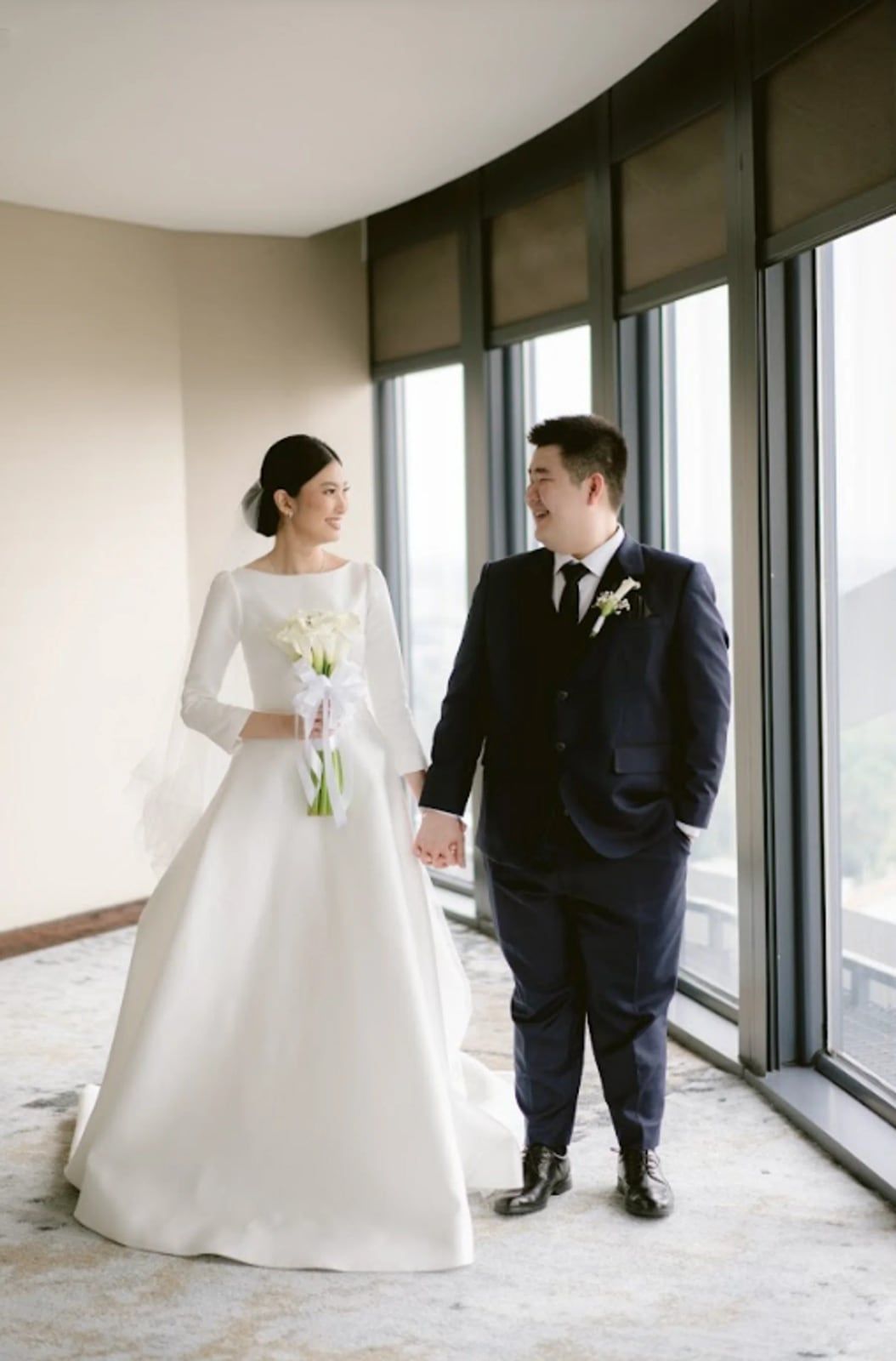 Jufrianto dan Novia bergandengan di depan jendela kamar hotel